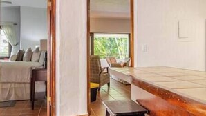 A room with a bed, a small table, and a view of greenery outside. - Cozy Golf Course View Villa inside the Wyndham Grand Rio Mar Resort (Rio Grande)