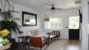 A living room with a sofa, coffee table, and chairs. There is a ceiling fan, a window with blinds, and a door. - Casita dos Robles Fallbrook's Favorite Dog-friendly Country Escape (Fallbrook)