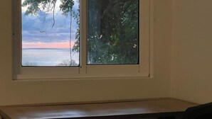 Ein Zimmer mit Fensterblick auf ein Gewässer und Bäume.