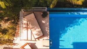 Une piscine à l’eau d’un bleu limpide, entourée d’une clôture blanche et d’une terrasse en bois.