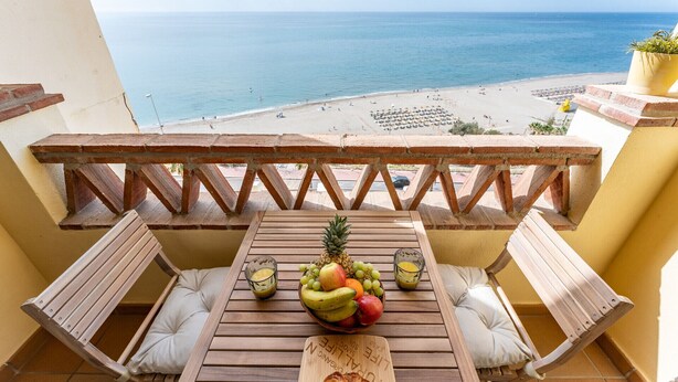 A wooden table with a fruit bowl and glasses on a balcony overlooking a beach. - Spectacular sea views parking and pool  REF006 (Benalmádena)