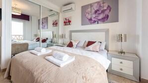 A modern bedroom with a large bed, bedside tables, a mirror, and artwork on the walls. - Spectacular sea views parking and pool  REF006 (Benalmádena)