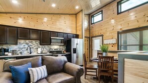 A cozy cabin interior with a kitchen, dining area, and a leather sofa. - Cozy 2BR | HOT TUB | Pets Welcome! (Sevierville)