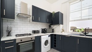 Una cocina moderna con armarios oscuros, lavadora integrada y microondas.