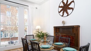 Un comedor con una mesa de vidrio, cuatro sillas, platos color turquesa y una chimenea.