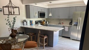 Una cocina moderna con gabinetes grises, una isla central y electrodomésticos de acero inoxidable.