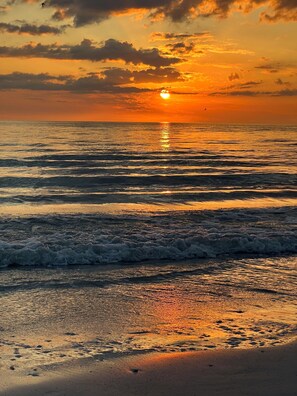 A sunset over the ocean with waves approaching the shore. - Beautiful Townhome with private patio / swimming pool and pet friendly ! (Fort Myers)