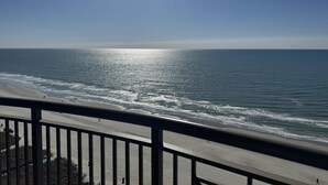 A beach view from a balcony with a railing, ocean waves, and a clear sky. - MVG 1512 Oceanfront, Penthouse (North Myrtle Beach)