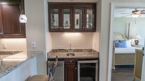 A kitchen with dark wooden cabinets, a granite countertop, and a stainless steel sink. - MVG 1512 Oceanfront, Penthouse (North Myrtle Beach)