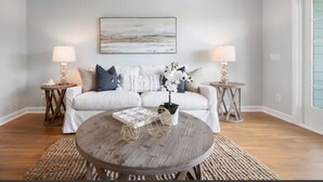 A living room with a sofa, two side tables, a coffee table, and a painting on the wall. - Charleston’s Folly! King Suite - Walk to Center St (Charleston)
