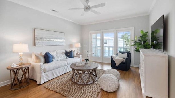 A living room with a white sofa, a round coffee table, and a ceiling fan. - Charleston’s Folly! King Suite - Walk to Center St (Charleston)