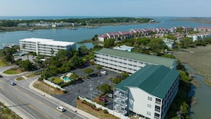 An aerial view of a hotel complex with multiple buildings, a parking lot, and a body of water in the background. - Charleston’s Folly! King Suite - Walk to Center St (Charleston)