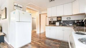 Une cuisine avec des armoires blanches, un réfrigérateur, une cuisinière et une machine à café.