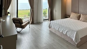 Une chambre d’hôtel moderne dotée d’un grand lit, d’un bureau avec une chaise et offrant une vue sur la mer.