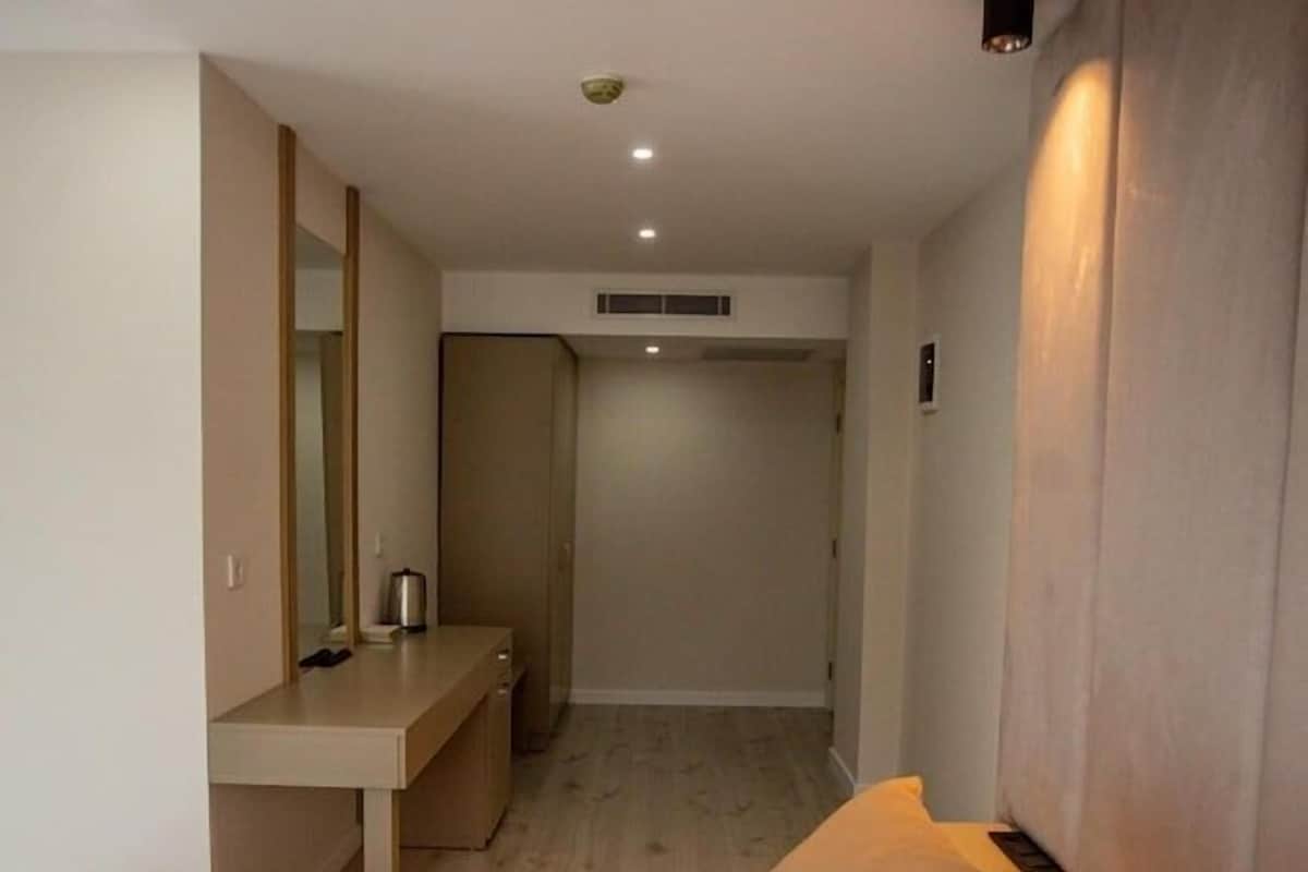 Una habitación de hotel con cama, mesita de noche y espejo.