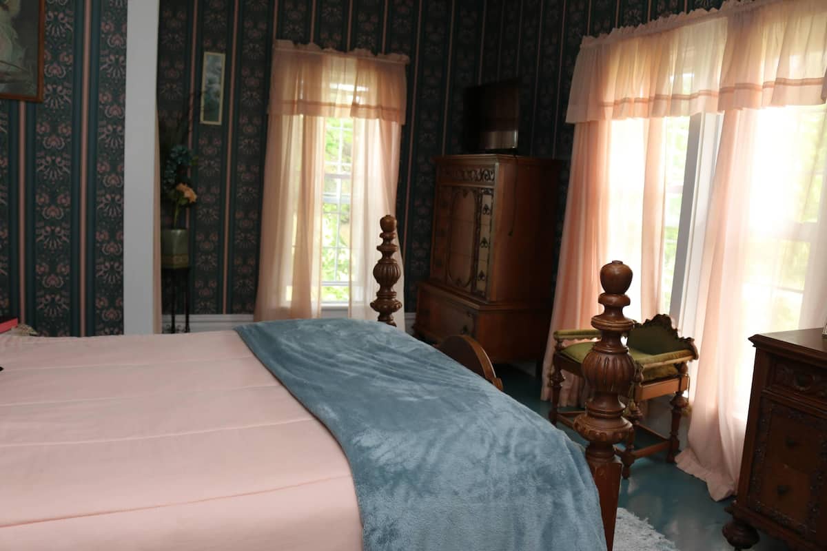 Une chambre à coucher comprenant un lit, une commode en bois, une chaise et un placard.