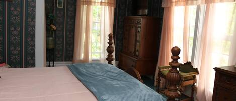 Une chambre à coucher comprenant un lit, une commode en bois, une chaise et un placard.