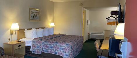 A hotel room with a bed, two bedside lamps, a chair, a desk, and a coat rack.