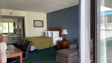 A hotel room with a bed, desk, chair, and a window with a view of the street.