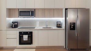 A modern kitchen with a built-in microwave, oven, and stainless steel refrigerator. - Master Suite DLX (Heredia)