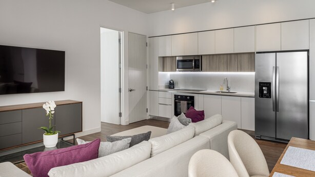 A modern kitchen with stainless steel appliances, a flat-screen TV, and a minimalist design. - Master Suite DLX (Heredia)