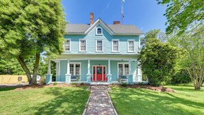 A two-story house with a red front door, a brick pathway leading to the entrance, and a well-maintained lawn. - Grand Historic Home w/ Yard & Deck in High Point! (High Point)