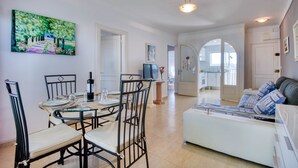 A dining area with a round table, chairs, and a painting on the wall.