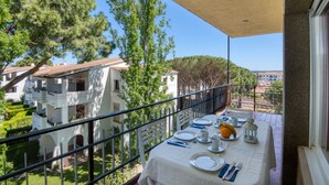 A balcony with a table set for dining, overlooking a residential area with houses and trees.