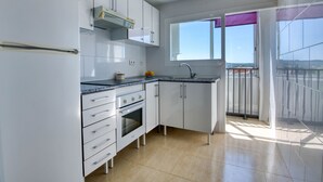 A modern kitchen with white cabinets, a built-in oven, and a window with a view of the outdoors.