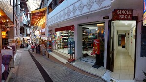 Une rue étroite bordée de boutiques des deux côtés, dont une, bien visible, porte le nom de « SINCHI ROCA ».