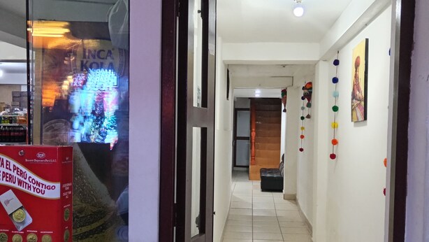 Un couloir avec un sol carrelé, un réfrigérateur Coca-Cola et une enseigne indiquant « SINCHI Roca ».