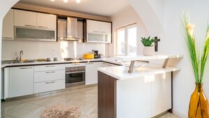 A modern kitchen with white cabinetry, a central island, and a built-in oven. - Apartments Sandito - Two Bedroom Apartment with Terrace and Sea View (Mlini)
