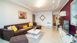 A modern living room with a brown sofa, a white coffee table, and a flat-screen TV. - Apartments Sandito - Two Bedroom Apartment with Terrace and Sea View (Mlini)