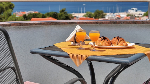 Une table avec un set de table jaune, deux croissants et deux verres de jus d’orange.