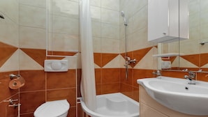 Une salle de bain avec des toilettes, une douche et un lavabo.