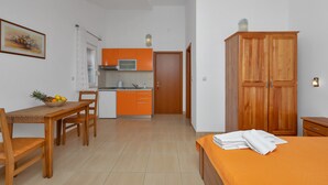 Une pièce de taille modeste comprenant une table à manger, des chaises, un lit et une armoire.
