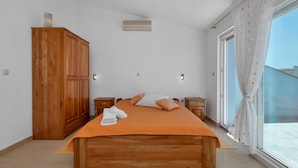 Une chambre à coucher avec un lit en bois, une armoire, des tables de chevet et une grande fenêtre avec des rideaux.