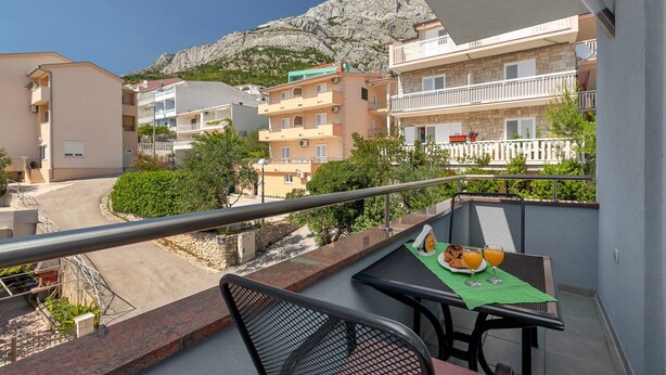 A balcony with a table set for breakfast, overlooking a street and buildings with a mountain in the background.