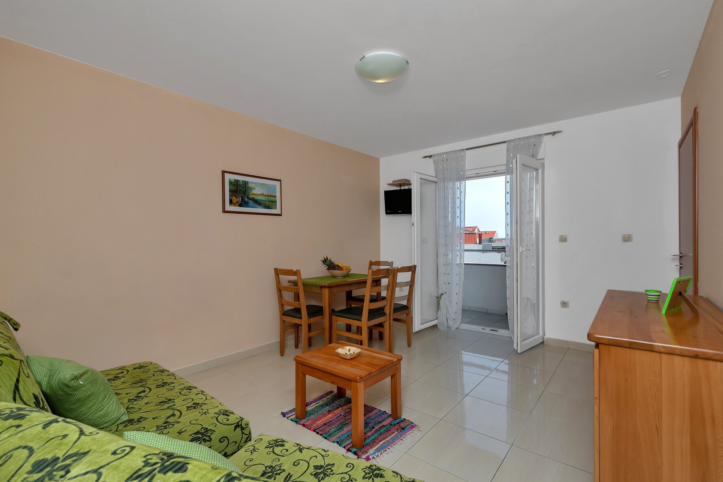 Ein Wohnzimmer mit einer Couch, einem Holztisch und einem Esstisch mit Stühlen.