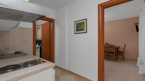 Una cocina compacta con un fregadero, estufa y una puerta que da a un comedor con mesa y sillas.