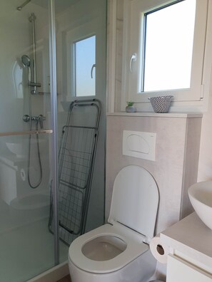 Une salle de bain moderne avec une douche à parois de verre, des toilettes blanches et un lavabo.