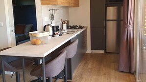 Une cuisine moderne avec des meubles hauts en bois, un réfrigérateur en acier inoxydable et un coin bar équipé de tabourets.
