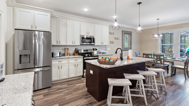 A modern kitchen with white cabinets, stainless steel appliances, a central island with stools, and pendant lighting. - Screened pool+Climate controlled game room+Outdoor TV+Fire pit+ Near the beach! (Navarre)