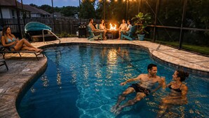A swimming pool with a fire pit and string lights, surrounded by a covered patio area. - Screened pool+Climate controlled game room+Outdoor TV+Fire pit+ Near the beach! (Navarre)
