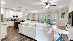 A spacious kitchen with white cabinets, a microwave, and a dining area with a large table and chairs. - Screened pool+Climate controlled game room+Outdoor TV+Fire pit+ Near the beach! (Navarre)