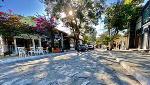 A street with a paved road, storefronts, and outdoor seating. - Pousada Luz da Lua (Búzios)