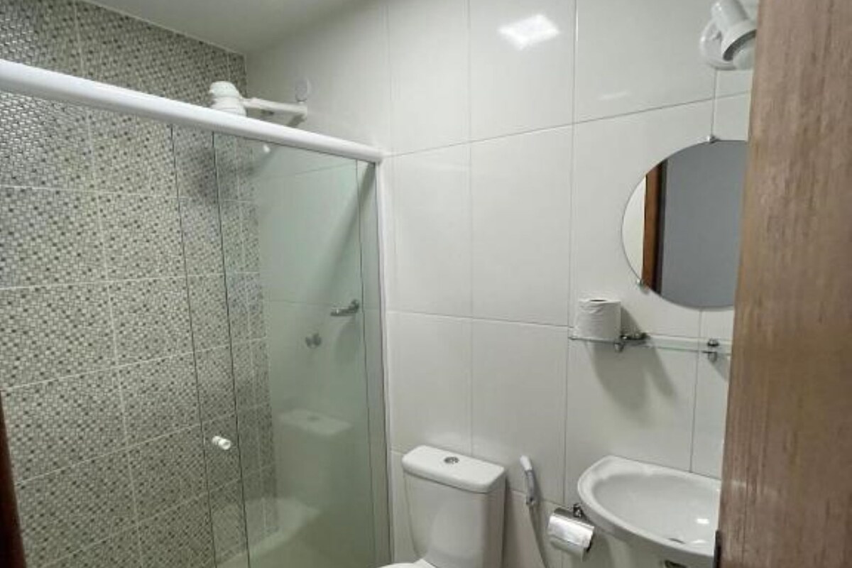 Moderni kylpyhuone, jossa on lasinen suihkuseinä, wc, pesuallas ja peili.