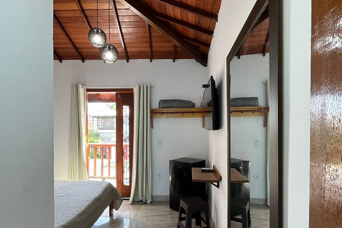 A bedroom with a bed, a desk, a chair, and a television.