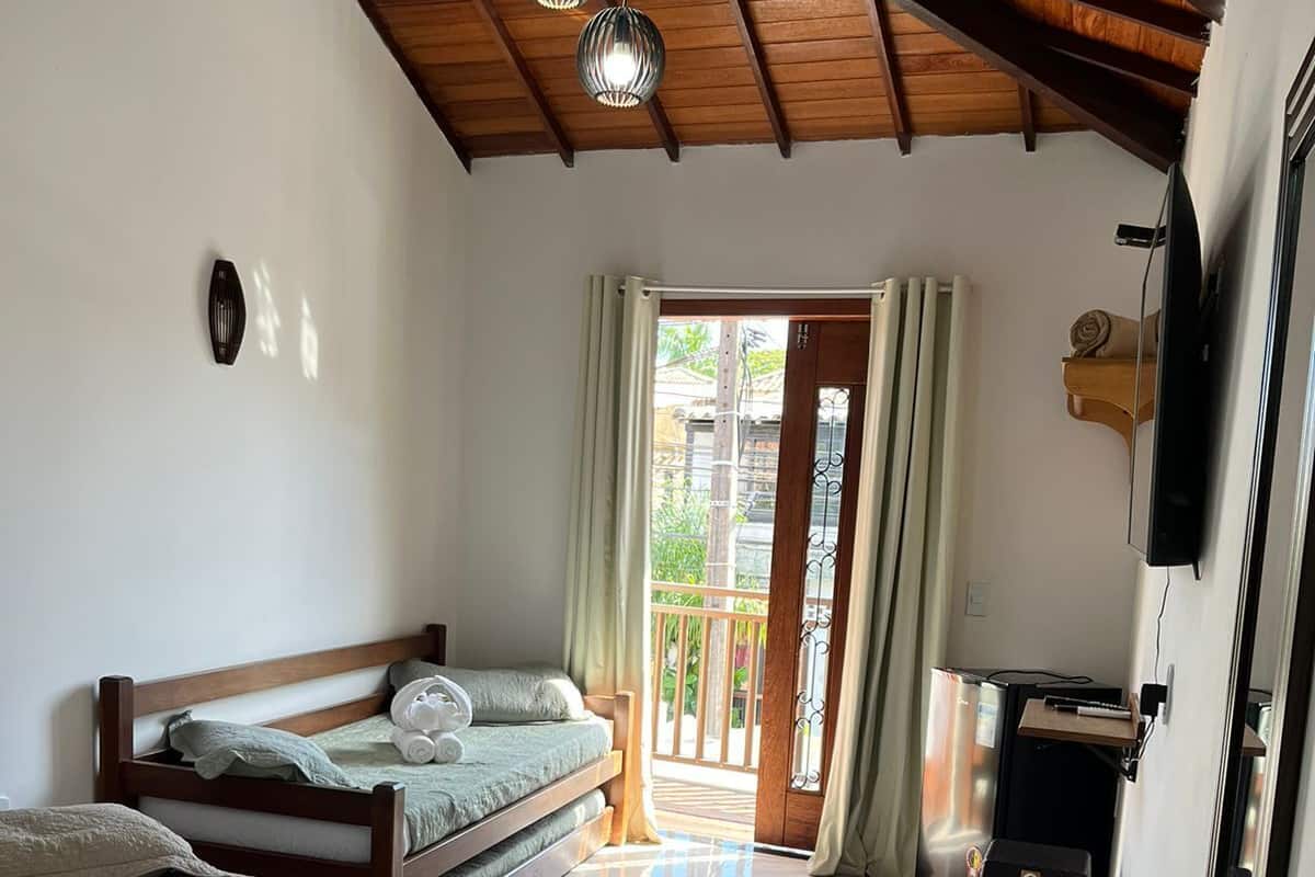 A bedroom with a bed, a desk, a TV, and a balcony.