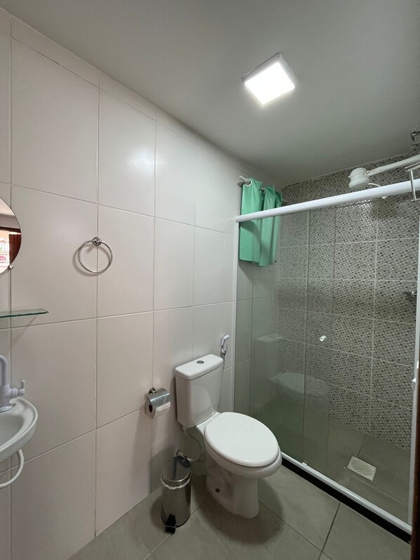 A bathroom with a toilet, a glass shower enclosure, and a toilet paper holder.